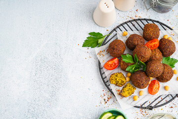 Stand with delicious falafel balls, chickpea and tomato on light background