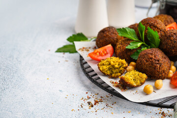 Stand with delicious falafel balls, chickpea and tomato on light background, closeup