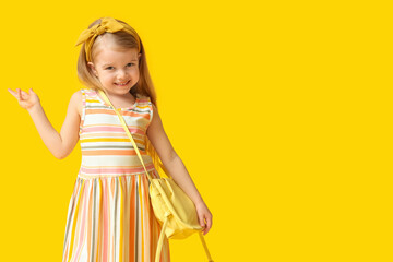 Cute little girl with stylish yellow bag on color background