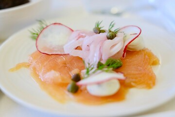 An entree of smoked salmon with herbed cream cheese, red radish, capers, pickled onion and a fresh...