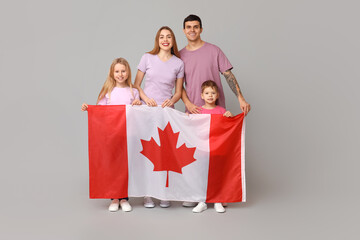 Happy family with flag of Canada on grey background