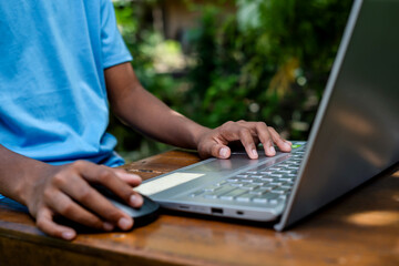 A child's hands on a laptop keyboard outdoors