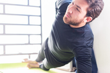 Hombre apuesto con barba practicando yoga en casa 