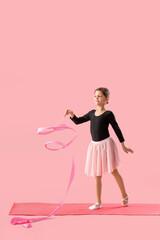 Little girl with ribbon doing gymnastics on pink background