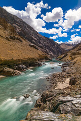 View of long exposure in portrait orientation of clear water flowing between snow covered mountains