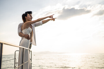 Asian young romantic couple looking at beautiful view during yachting.