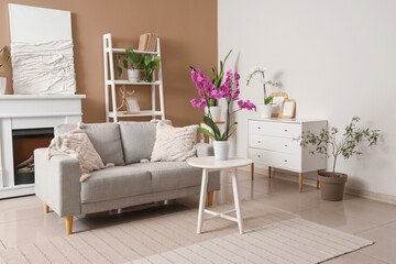 Interior of living room with sofa, drawers and orchid flowers