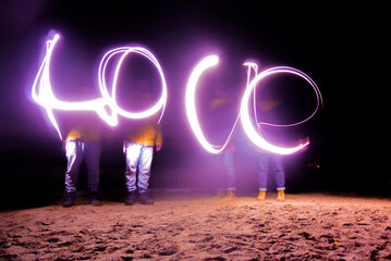 Night photo in motion with soft blur and long exposure. Married couple wrote word Love in purple...
