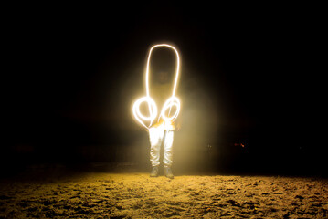 Night photography in motion with soft blur and long exposure. Man drew line drawing of headphones...