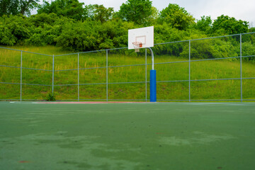 Outdoor basketball court in a park where people can enjoy playing and recreational activities.