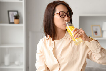 Young Asian woman drinking lemon water at home, closeup
