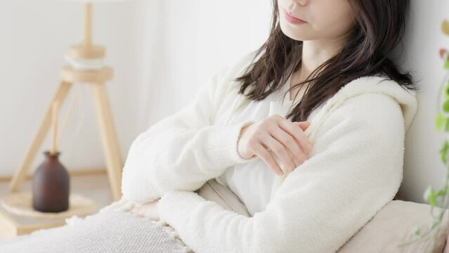 朝、ベッドで悩む女性