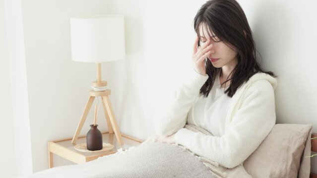 朝、ベッドで悩む女性