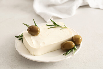 Plate with tasty feta cheese, olives and rosemary on white background
