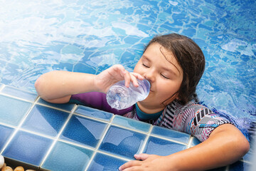 Child drinks water in the pool on vacation