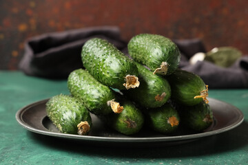Plate with fresh cucumbers on green table