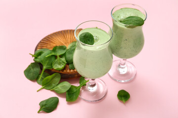 Glasses of fresh spinach smoothie on pink background