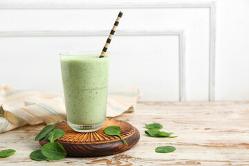 Glass of fresh spinach smoothie on white wooden table