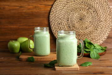 Mason jars of fresh spinach smoothie on wooden background