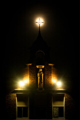Here is the Steeple, See all the People. Dark and omnious church building. A place of whorship at night with christ on the cross, moon rising behind a crucifix. Warmly lit chapel in darkness