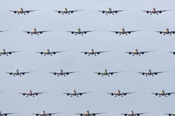 Composite photo, a grid pattern of approcahing aircraft. Large airliner incoming to land spaced out evenly vertically and horizontally. Airplanes fill the sky in a digitally altered pattern