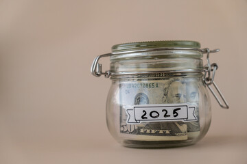 Glass jar full of American currency dollars cash banknote with text 2025 year. Preparation saving...