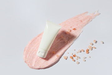 A white tube featured on a pink cream smudge, photography template for advertise nature skincare...