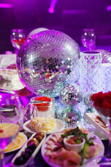 A table set for the holiday in purple in a dark banquet hall. 