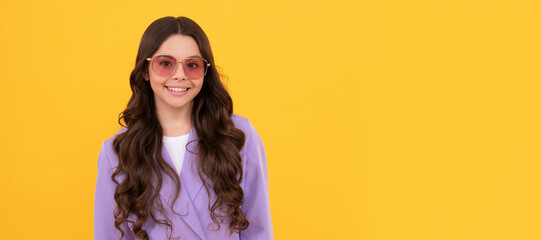 beautiful happy kid in stylish purple jacket and sunglasses on yellow background. Child face, horizontal poster, teenager girl isolated portrait, banner with copy space.