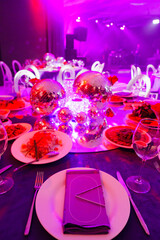 A table set for the holiday in purple in a dark banquet hall. 