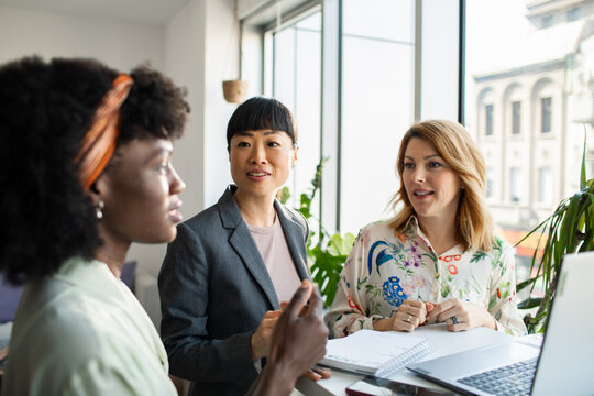Diverse young female colleagues with laptop in modern office - Powered by Adobe