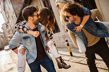Happy couples piggyback riding and laughing on city street