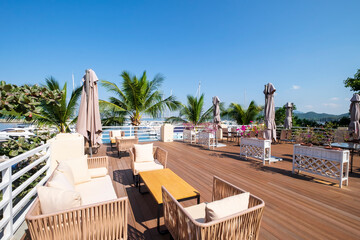 Fototapeta premium White Furniture Adorns Outdoor Wooden Deck Overlooking Sanya, Hainan Marina.
