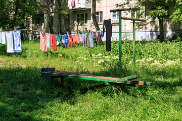 A green bench sits in a grassy field with clothes hanging on a clothesline