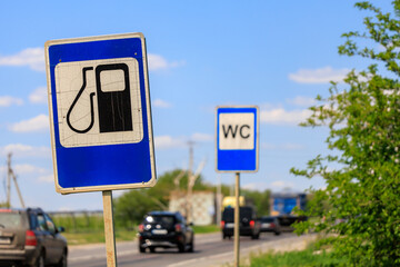 A sign for a gas station is on the side of a road