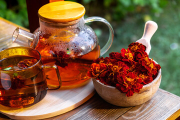 Marigold tea still life on table in green garden background. Healthy hot drink benefits. Natural...