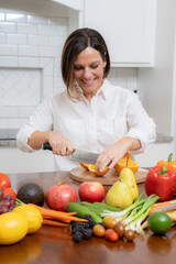 Friendly looking woman with brown bob chopping fruit in kitchen