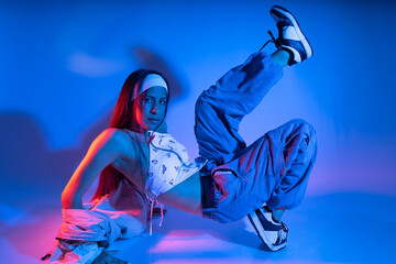 A woman is doing a dance move in front of a blue background