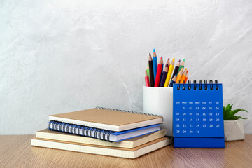 Notebook and pencil cup and calendar on table. Work desk space