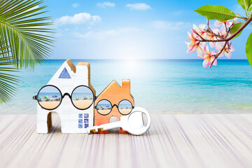Miniature house with beach sunglasses over tropical beach background, summer house, summer season holiday and vacation destination, beach house