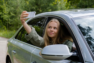 Blonde woman stoped car on road to take a selfie photo. Young tourist explore local travel making...