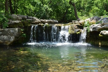 A hidden waterfall cascading into a crystal-clear pool in the heart of an enchanted forest
