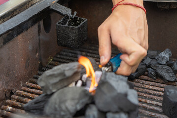 A man lighting a barbecue using charcoal