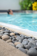 Stones decorating the edge of a turquoise swimming pool