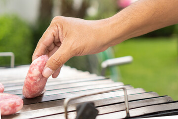 Man adding meat to a barbecue in the garden