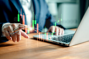Businesswomen use laptop computers to analyze virtual screens of graph stock market changes,...