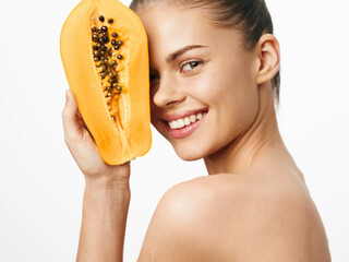 Portrait of a woman holding a ripe papaya fruit in front of her face on a white background