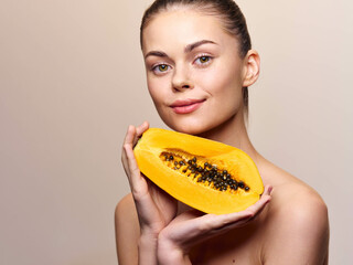 Attractive female holding fresh papaya fruit and making eye contact with camera, tropical healthy...