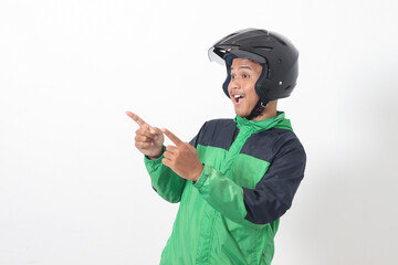 Portrait of Asian online taxi driver wearing green jacket and helmet pointing at empty space with finger. Isolated image on white background