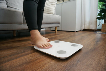 Fat diet and scale feet standing on electronic scales for weight control.	